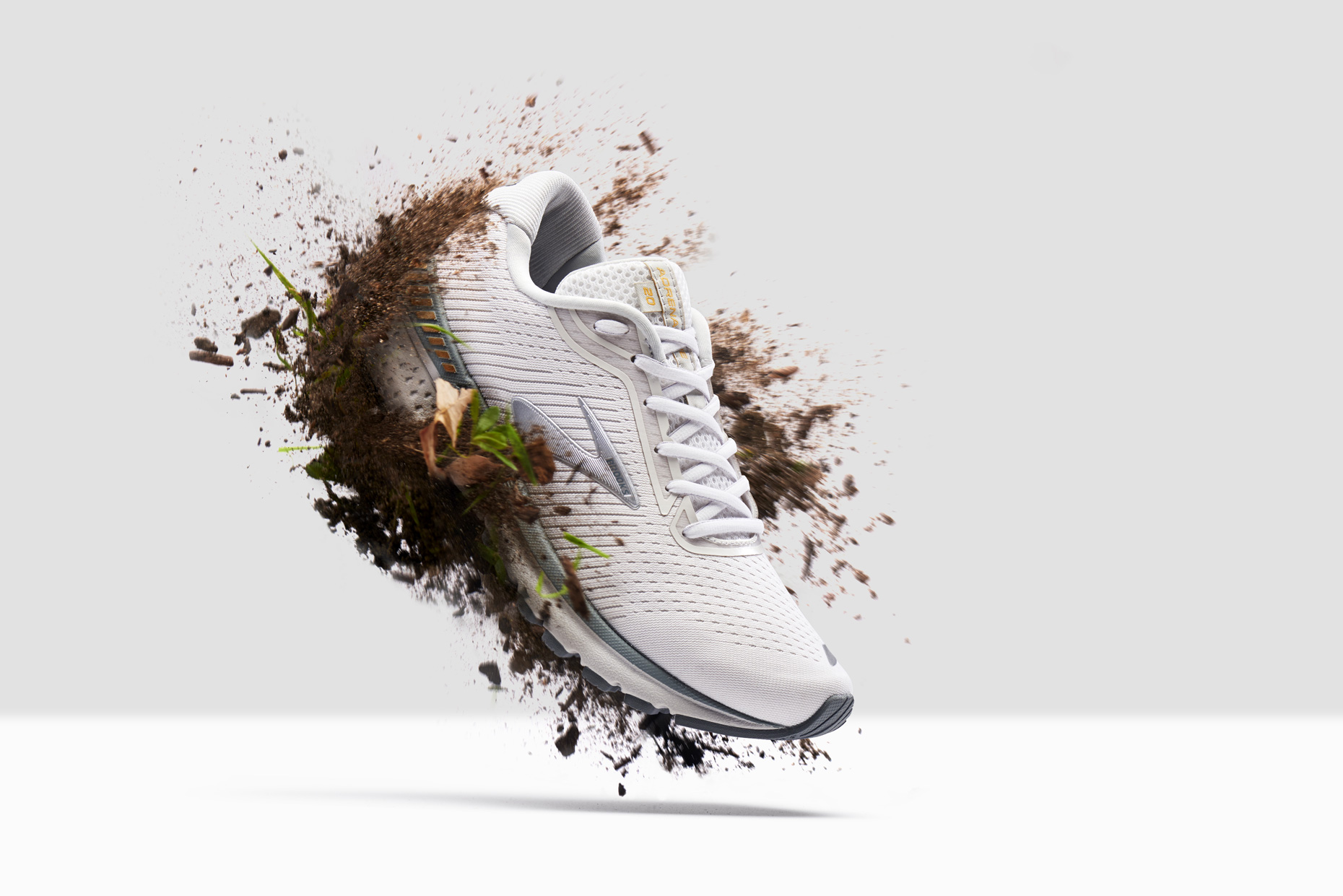 Brooks Trail Running Shoe hovering with dirt splashing, by still life photographer Adrian Mueller New York