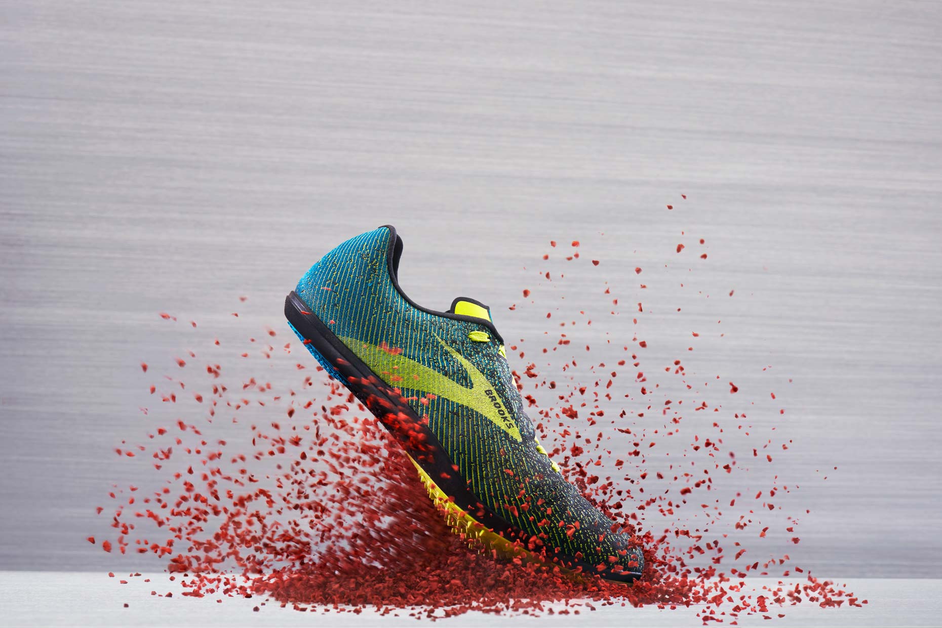 Brooks Track Running Shoe on a red track, by still life photographer Adrian Mueller New York