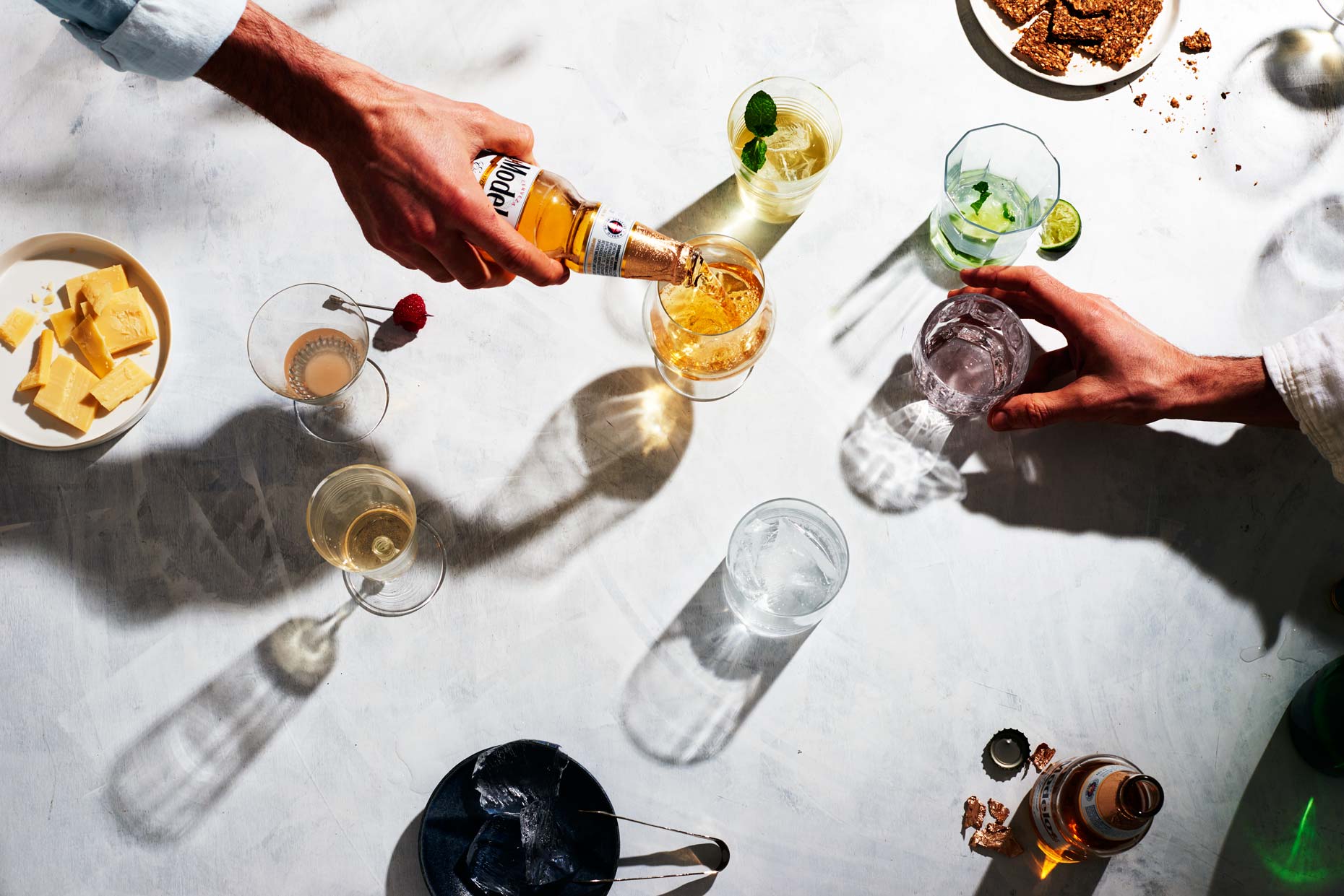 Hand pouring beer into glass on big table with drinks, photo by Food and Beverage Photographer Adrian Mueller New York